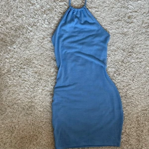Blå strandklänning/coverup - Strandklänning/coverup klänning från H&M. Har en halterneck-design som knyts i nacken och är tillverkad i ett mjukt material.
