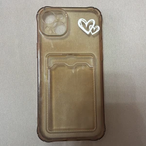 Transparent mobilskal med hjärtdekor - Säljer ett transparent mobilskal med en söt hjärtdekor i vitt. Skalet har en praktisk kortficka på baksidan, perfekt för att förvara kort eller ID. Passar utmärkt för dig som vill ha både stil och funktion i ett.