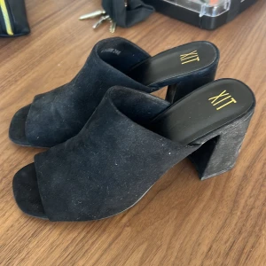 Svarta klackskor från Dinsko - Snygga svarta klackskor från Dinskos märke XIT i mocka med öppen tå och bred klack. Använda ute vid 2 tillfällen men har lite damm på sig då dem enbart stått.