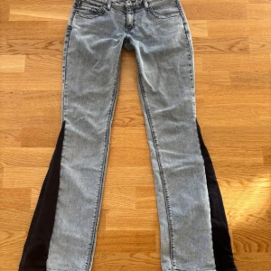 Snygga Levi’s jeans - Snygga jeans från Levi's med unika svarta paneler längs sidorna (egensydda) De har en klassisk femficksdesign och knappgylf. Perfekta för en cool och avslappnad stil. Lite slitna längs ner och bootcuten har jag sytt själv. Mått: midjemått tvärsöver 38 cm, midje höjd 21 cm, innerbenslängd 83 cm.