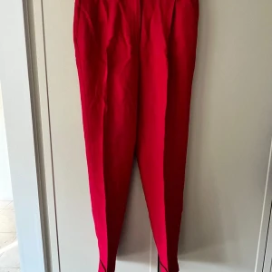 Röda byxor från Massimo Dutti - Snygga röda byxor från Massimo Dutti med en elegant och stilren design. Perfekta för att lägga till en färgklick i garderoben. Tillverkade i Portugal.