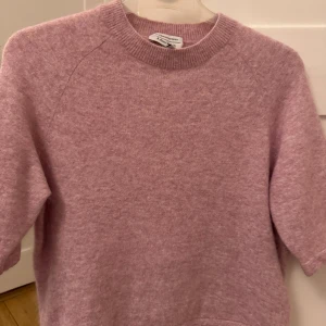 Rosa tröja från & Other Stories - Säljer en mjuk och stilren rosa tröja från & Other Stories. Tröjan har en rund halsringning och korta ärmar, perfekt för en avslappnad look.