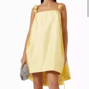 Gul  klänning med blommor - Oanvänd gul klänning med flyttbara blommor  som går att sätta fast på banden eller om man vill forma klänningen i midjan etc. Perfekt för sommaren. Köpte den till min examen men säljer då jag hittade en annan, aldrig använd🤗