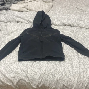 Svart fleecejacka med huva - Mysig svart fleecejacka med dragkedja och huva. Perfekt för kyliga dagar. Jackan har långa ärmar och en enkel design som passar till det mesta.