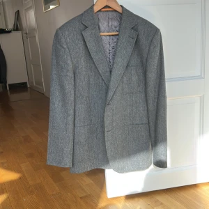 Lättfodrad kavaj/blazer från Mads Nörgaard - Grå lite tweedaktig kavaj från Mads Nörgaard i väldigt bra skick. Inga skavanker, knappt använd. Lappar på armbågarna. Nypris ca 3500:-