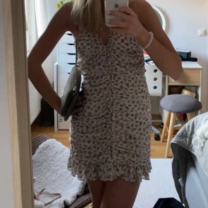 blommig klänning zara  - Säljer en söt axelbandslös klänning med blommigt mönster i rosa och blått. Klänningen har en smickrande rynkad design och volangdetaljer längst ner. Perfekt för sommarens varma dagar! Storlek S