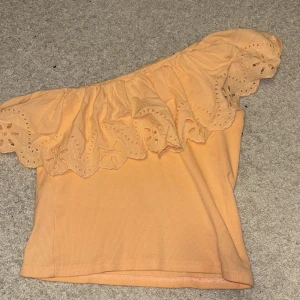 Persikofärgad offshoulder topp från Zara - Säljer en söt persikofärgad offshoulder topp från Zara med vackra spetsdetaljer. Perfekt för varma dagar med sin luftiga design och ribbade material. Passar både till jeans och kjol för en chic look. 🌸