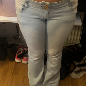 Ljusblå jeans med låg midja - Snygga ljusblå jeans med låg midja och bootcut-stil. De har en femficksdesign och stängs med en dragkedja och treknappar framtill. Stl xl men passar M/38, köpta utomlands