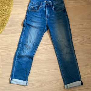 Blå jeans från LAB Industries - Snygga blå jeans från LAB Industries med relaxed fit. De har en klassisk femficksdesign och uppvikta benslut för en trendig look. Perfekta för en avslappnad stil. Storlek 140/10Y. Priset är inte hugget i sten och kan sänkas vid snabb affär. 