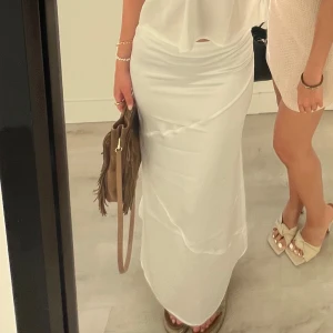 Vit långkjol - Sån elegant långkjol från NAKD i siden. Det är en liten slits på sidan vilket gör att den blir enkel att gå i🙌🏽 På sista bilden ser man på vänstra sidan av midjan att det är som en liten tråd som gått upp men absolut inget man tänker på!!💕💕