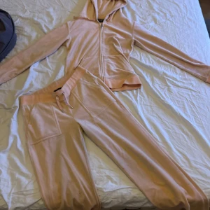 Rosa hoodie från Juicy Couture - Säljer en mjuk kofta och bekväma byxor i färgen rosa  från Juicy Couture. Den har en dragkedja framtill och en klassisk huva. Perfekt för en avslappnad stil. 💖