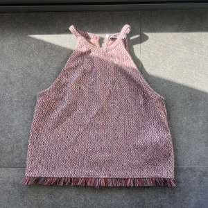 Mönstrad ärmlös topp med fransar från zara  - Säljer en snygg ärmlös topp med ett småmönstrat tryck i rött och vitt. Toppen har dekorativa fransar längs nederkanten och en bekväm passform. Säljer även matchande kjol som ser och kan ge ett set pris isånfall