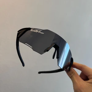 Svarta sportglasögon från TechFit Gear - Snygga och futuristiska svarta sportglasögon från TechMe Gear. De har en bred, omslutande design med tonade linser som ger ett coolt och modernt utseende. Perfekta för utomhusaktiviteter och träning.