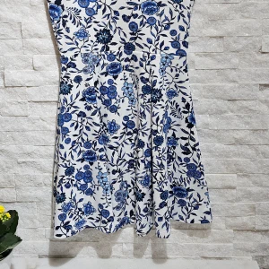 Blommig klänning från H&M Divided - Säljer en söt blommig klänning från H&M Divided i storlek S. Klänningen har ett vackert blått och svart blommönster på vit bakgrund. Den är ärmlös med en smickrande passform och rund halsringning.