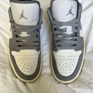 Grå och vita Nike Air Jordans - Snygga Nike Air Jordans i grått och vitt med klassisk snörning och perforerad tå. Använda få gånger dom är i bra skick. köpte för 2900