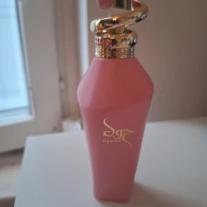 Hawwa Pink parfym från Zimaya 100 ml - Hawwa Pink från Zimaya är en parfym i en snygg rosa flaska med guldiga detaljer och en unik spiralformad kork. Doften är blommig och fruktig med inslag av ros, citrus, tropiska och fräscha toner. Perfekt för dig som gillar feminina och moderna dofter. Endast testad några gånger. 
