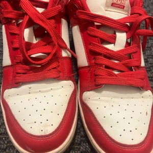 Rödvita sneakers från New Yorker - Snygga sneakers i rött och vitt från New Yorker med broderad USA-text på hälen. Skorna har klassisk låg siluett, snörning och perforerad tå. Ovandelen är i syntetmaterial och insidan är fodrad i rött tyg. Perfekt för dig som gillar sportig och retro stil. Passar även till vanliga dagar🙌.