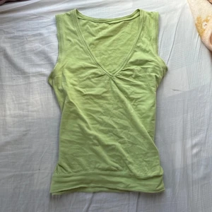 Ljusgrön ärmlös linnetopp - Snygg ljusgrön linnetopp med djup v-ringning och bredare axelband. Toppen är i mjuk bomull och har en enkel, clean look som passar perfekt till jeans eller kjol. Lätt rynk vid bysten för en extra detalj.