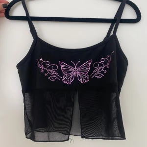 Topp med fjäril  - Jättefin Svart topp med rosa fjäril i stenar. Knappt använd.