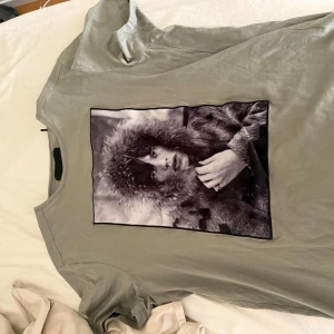 Grå t-shirt Limitato x Terry O'Neill - Tjena säljer nu min Snygga grå t-shirt från Limitato med stort svartvitt fotoprint av Terry O'Neill på bröstet. Klassisk rund hals och korta ärmar. Mjuk bomullskänsla och modern passform, perfekt för dig som gillar unika statement-plagg. Rensade min garderob och tänkte att de dax o sälja då jag inte använder längre! Använd ca 5-10 gånger och bara legat i min garderob!