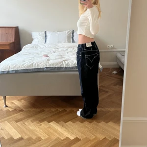 Levis 501 mörkblå jeans loose fit - Mörkblå Levis 501 jeans med kontrastsömmar och klassiska bakfickor. Modellen är loose fit med raka ben och låg midja. Jeansen är tillverkade i kraftigt denimtyg.