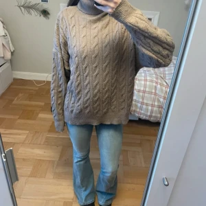 Beige kabelstickad polotröja - Mysig beige polotröja med kabelstickat mönster och oversized passform. Tröjan har långa ärmar och hög krage som ger en chill och trendig vibe. Perfekt för lager-på-lager och att hålla sig varm under kyliga dagar. Har använts mycke men fortfarande i fint skick💞 eventuellt lite lite nopprig men det är absolut inget man tänker på (se bild 2)🫶🏼