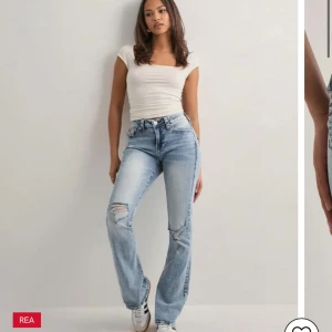 True Religion Becca Bootcut Jeans - Säljer ett par ljusblå True Religion Becca jeans med bootcut och midwaist. Jeansen har slitningar på ena knät, klassiska röda sömmar och snygga detaljer på bakfickan. Perfekt för dig som gillar en avslappnad men trendig look. Använda en enstaka gång 