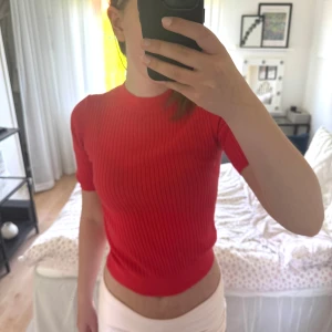 Koralröd uniqlo T-shirt - En korall röd stickad T-shirt från uniqlo i storlek S. Den är använd ett fåtal gånger och är i ett väldigt bra skick.