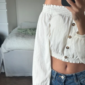 Vit offshoulder croppad blus XS - Superfin vit offshoulder blus med croppad passform och långa puffiga ärmar. Toppen har snygga bruna knappar framtill och smockad resår upptill och nedtill. Perfekt till jeans🩷