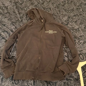 Svart hoodie från Peak Performance L - Svart hoodie från Peak Performance med dragkedja, huva med snörning och broderad logga på bröstet. Mjuk insida och stora fickor framtill. Perfekt för chill dagar eller när du vill ha en avslappnad look.