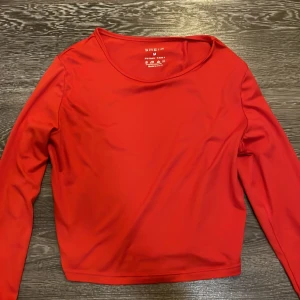Röd långärmad topp från SHEIN - Snygg röd långärmad topp från SHEIN i stretchigt material. Modellen är croppad med rund halsringning och sitter tajt mot kroppen. Perfekt för dig som vill ha en enkel men färgstark bas i garderoben. Det står M på tröjan men den passar mer för S och XS.
