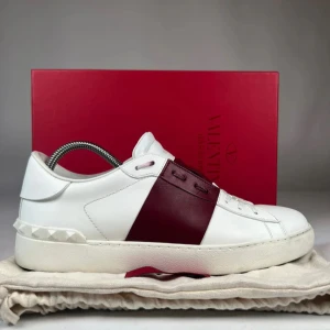Valentino  Open sneakers i vitt och vinrött - Säljer ett par snygga Valentino Garavani Open sneakers i vitt skinn med bred vinröd rem över vristen. Dessa skor är i princip helt nya med minimala täcken på användning. Storlek 41 men passar 42. Om ni har några frågor så är det bara att kontakta❤️‍🔥
