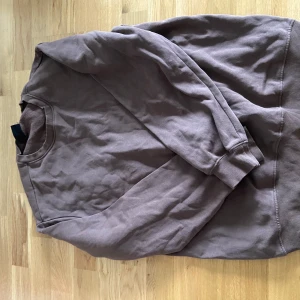 Brun sweatshirt från H&M - Säljer en brun crewneck sweatshirt från H&M med relaxed fit. Tröjan har rund halsringning och långa ärmar, perfekt för en avslappnad stil. Passar bra till jeans eller mjukisbyxor.