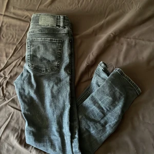 Svarta jeansbyxor från Jack & Jones - Säljer ett par svarta jeansbyxor från Jack & Jones med klassisk femficksdesign och raka ben. Byxorna har normal passform och är tillverkade i ett slitstarkt denimtyg. Perfekta för dig som gillar en enkel och stilren look.