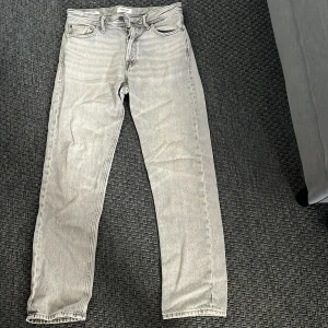 Jack & jones jeans - Säljer ett par ljusgrå jeans från Jack & jones med klassisk femficksdesign och raka ben. Byxorna har normal passform och är perfekta för dig som gillar en stilren look. 