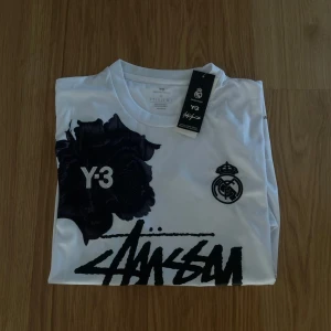 Real Madrid Stussy t-shirt - Säljer en vit riktig snygg Real Madrid Stussy fotbollströja. Denna är väldigt snygg och perfekt till sommaren. Skicket på denna är ny med lapp och 10/10. Storleken är M. Priset jag kommer sälja denna för är 399kr men kan tänka mig sänka vid snabb affär. Kontakta mig vid frågor.