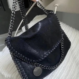 Svart axelväska med kedjedetaljer - Tiamo väska köpt förra året knappt använd då jag är guldtjej och banden på väskan är silver/svarta💕 bra skick