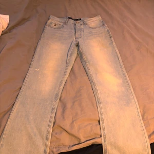 Ljusblå loose fit jeans från Rocawear - Säljer ett par ljusblå jeans från Rocawear med loose fit och raka ben. Jeansen har broderade bakfickor med vit design och klassisk femficksmodell. Märkespatch i brunt på baksidan av midjan och metallknapp framtill. Storlek 32/32.   Tyvärr är det lite defekter på högerben.
