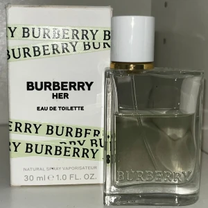 Burberry Her Eau de Toilette 30 ml - Fräsch och modern parfym från Burberry i en stilren, transparent glasflaska med vit kork och gulddetalj. Doften är lätt och feminin, perfekt för dig som gillar eleganta och fruktiga toner. Kommer i originalförpackning med Burberrys klassiska logga.