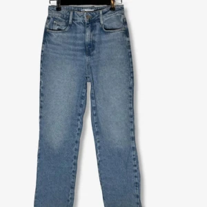 Blå raka jeans från Zara - Klassiska blå jeans från Zara med raka ben och hög midja. Jeansen har fem fickor, bälteshällor och stängs med knapp och dragkedja. Perfekta till vardags och enkla att matcha med olika toppar.