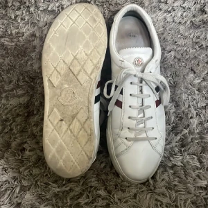 Moncler skor - Säljer ett par vita Moncler skor i storlek 45           Bra skicka snygga och bra för sommaren