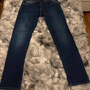 Replay jeans blå - Säljer ett par klassiska blå jeans från Replay med snygga bakfickor och kontrastsömmar. Modellen har normal passform och raka ben, perfekt för en stilren look. Märkta med Sustainable Lab och Replay-logga på insidan.