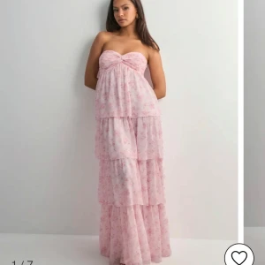 Nelly rosa långklänning - Dreamy frill dress från Nelly med blommor på. Helt ny, enbart testad. Nypris är 699kr. Säljer pga att den var för stor för mig. 