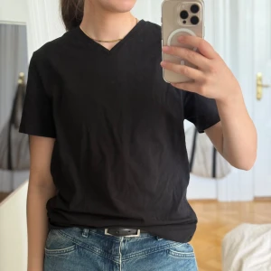Svart v-ringad t-shirt från H&M - Säljer denna svarta T-shirt med v-ringning från H&Ms herravdelning. Den är knappt använd och är i mycket fint skick!