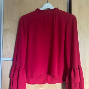 Blus - Fin röd blus, kan än vändas till mycket! Har lite volanger vid armarna, lite små fläcker men dom syns knappt