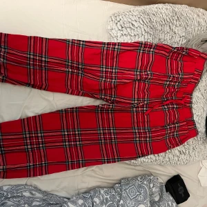 Röda rutiga byxor pyjamas byxor  - Säljer ett par röda pyjamas byxor med klassiskt rutigt mönster och resår i midjan. Perfekta för dig som vill sticka ut med färg och mönster. Byxorna har en rak passform och är superbekväma.