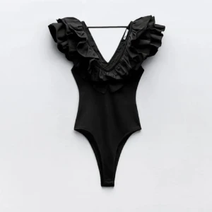 Svart body med volang och djup v-ringning - Svart body med djup v-ringning och stora volanger runt halsen och axlarna. Helt slutsåld💓sista bilden är min! Lägg prisförslag. Storlek m men sitter som en xs. Har lapp kvar!