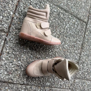 Beige kilklack sneakers med kardborreband - Säljer ett par beige boots med högt skaft och två breda kardborreband. Skorna har en rund tå, platt sula och detaljer i både slätt och perforerat syntetmaterial. Insidan är vadderad för extra komfort och yttersulan är i gummi. Likt de iconic Isabel Marant skorna. alltså INTE ÄKTA Isabel Marant. Står 35 men är som 36, passar mig som är 36