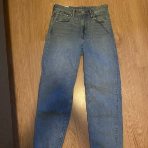 Blå loose fit jeans från H&M - Säljer ett par blå loose fit jeans från H&M. Klassisk femficksmodell med knapp och dragkedja i gylfen. Jeansen har raka ben och en avslappnad passform, perfekta för en chill och trendig look.
