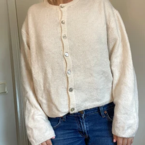 Supermysig stickad kofta med knappar💖💖🙌 - Mysig vit stickad kofta med rund hals och silvriga knappar framtill. Koftan har lång ärm och en rak, något loose passform. Använd fåtal gånger. Märke Gina Tricot